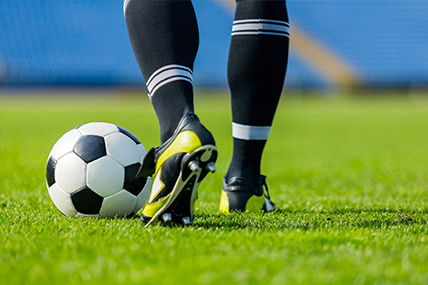 Imagem de pernas de jogador de futebol a preparar pontapé na bola 