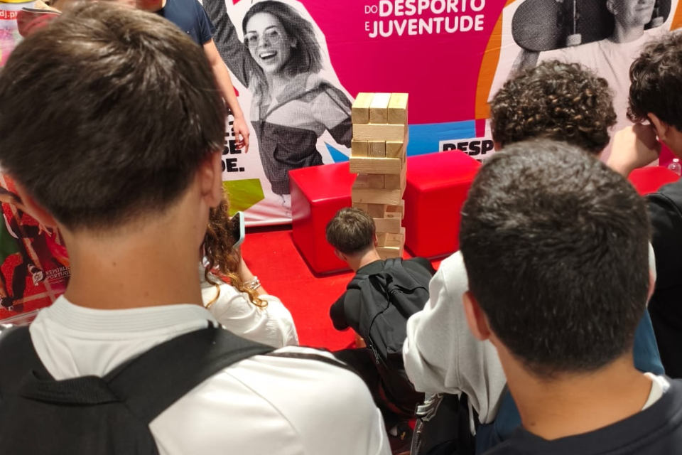 Jovens no stand do IPDJ a jogar jenga gigante.