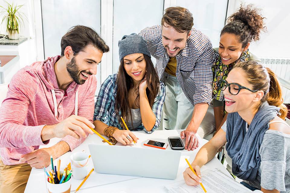 grupo de jovens numa mesa com um computador