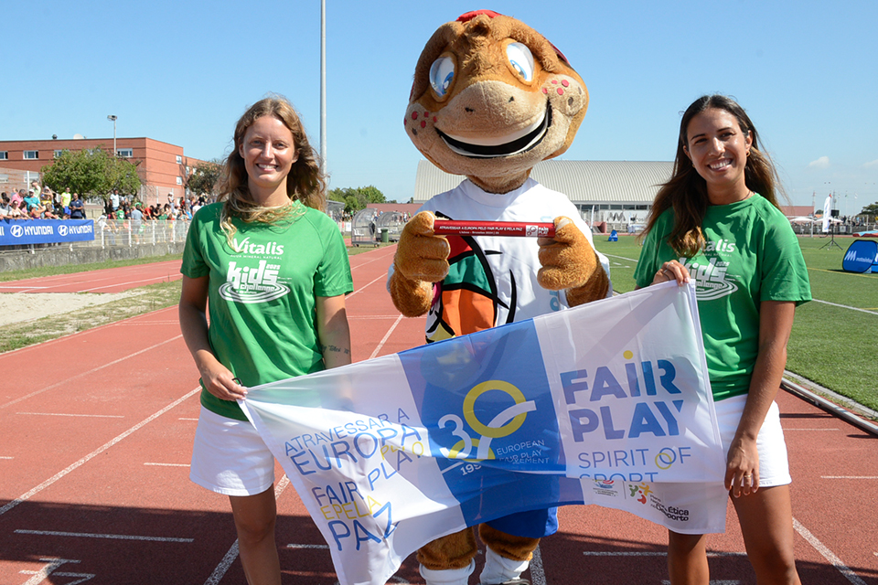 Foto de mascote com o testemunho de estafeta