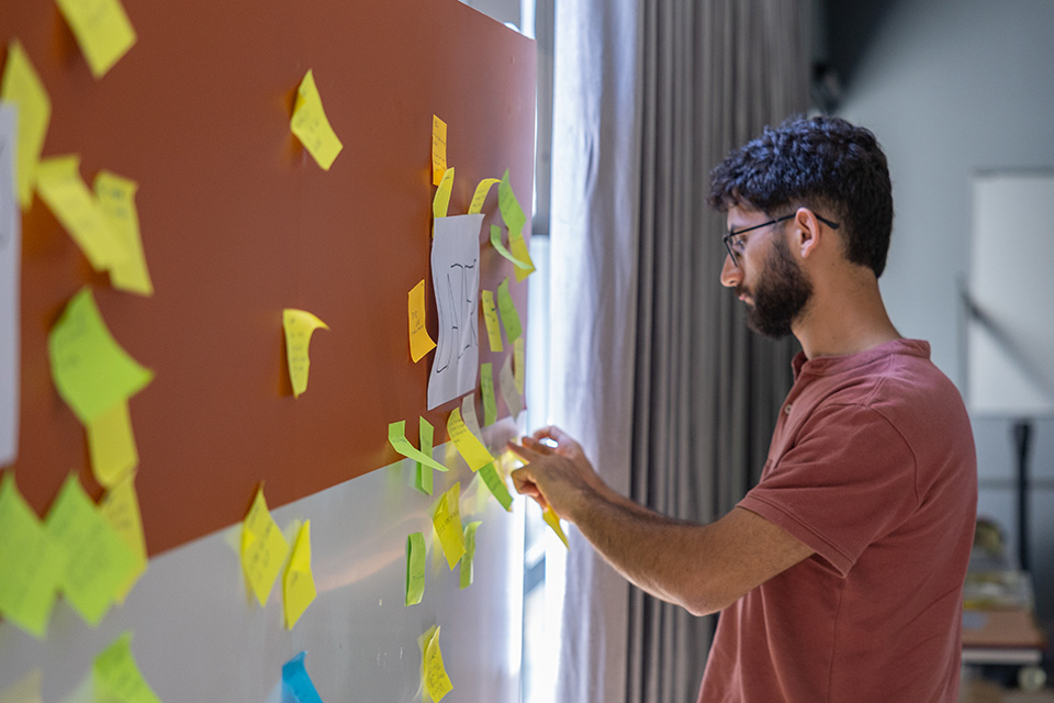 Jovem a colocar post-it em quadro com palavras chave