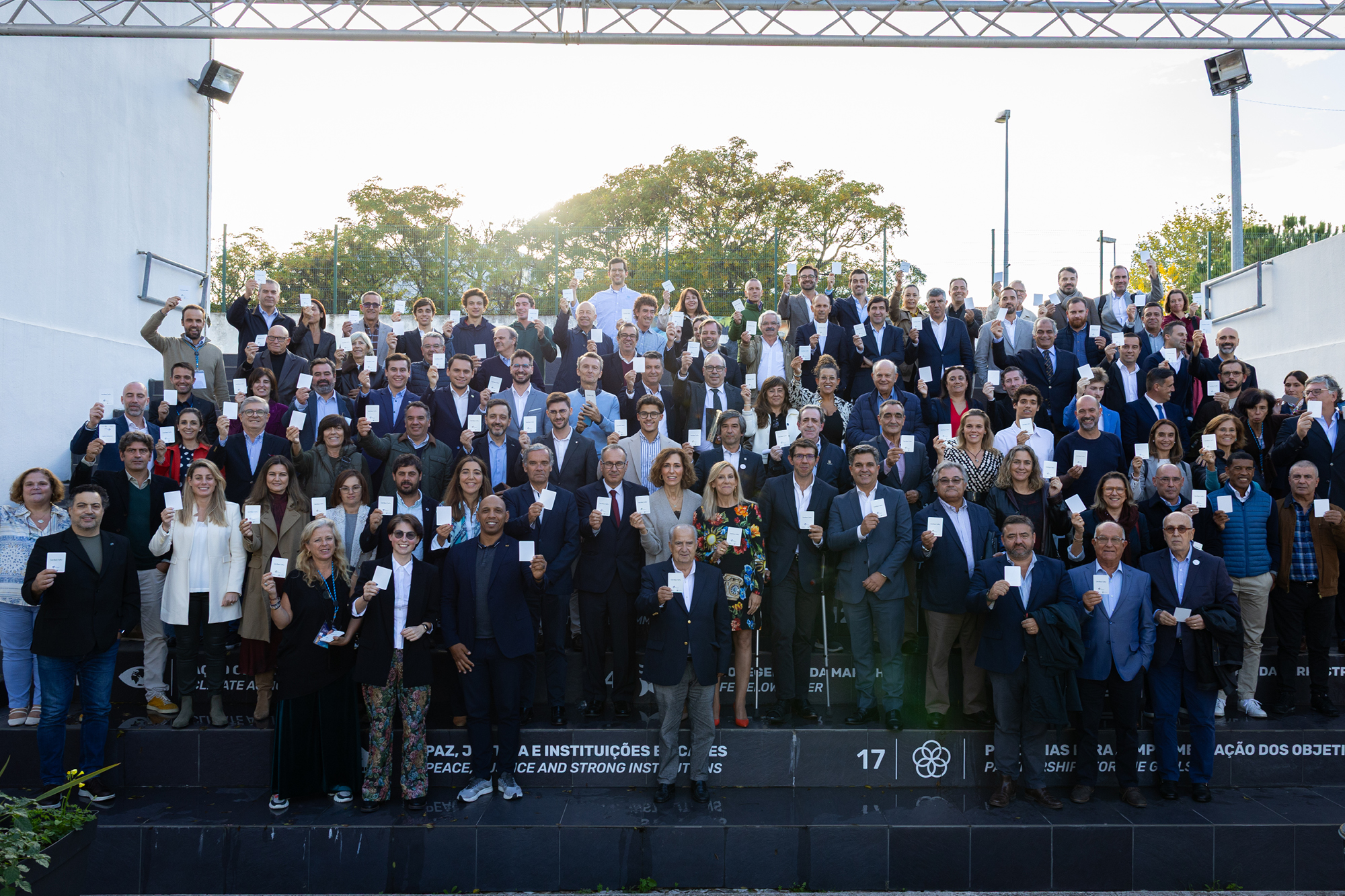 Imagem de todos os participantes e convidados na rua com o cartão branco na mão