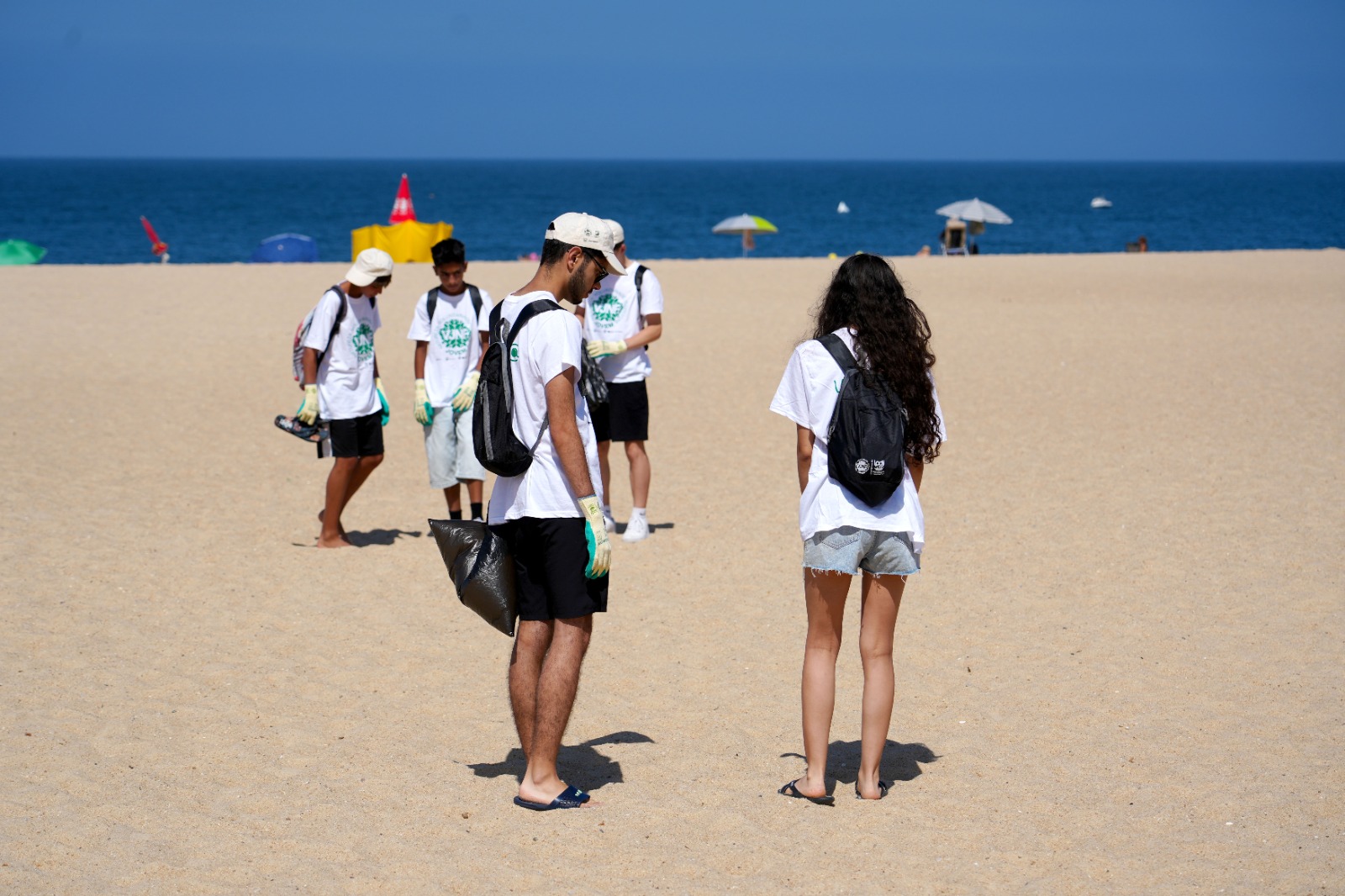 jovens voluntários a limpar o areal