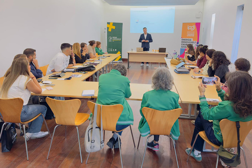 Participantes do Programa Novas Lideranças  Para um Desporto mais Igual assistem a uma sessão de formação numa sala de reunião, com apresentação projetada e materiais de trabalho distribuídos pelas mesas.