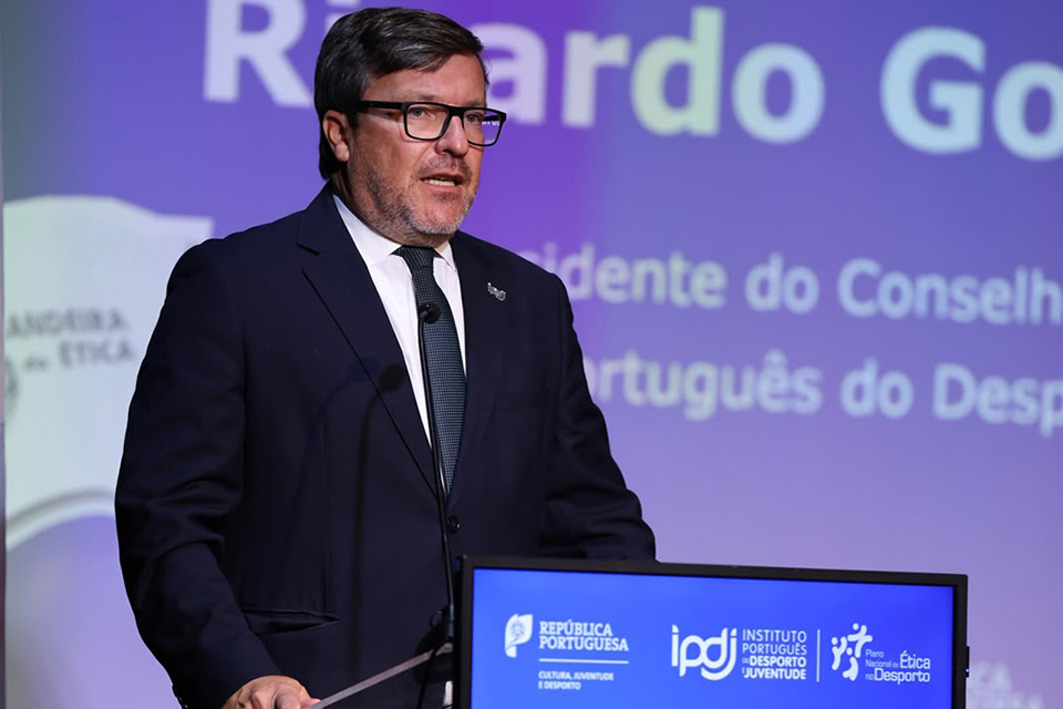 presidente do IPDJ a discursar num púlpito durante uma cerimónia da Bandeira da Ética.