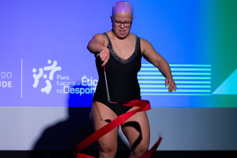 Atleta do Ginásio Clube Português realiza exercício com fita durante atuação em palco.