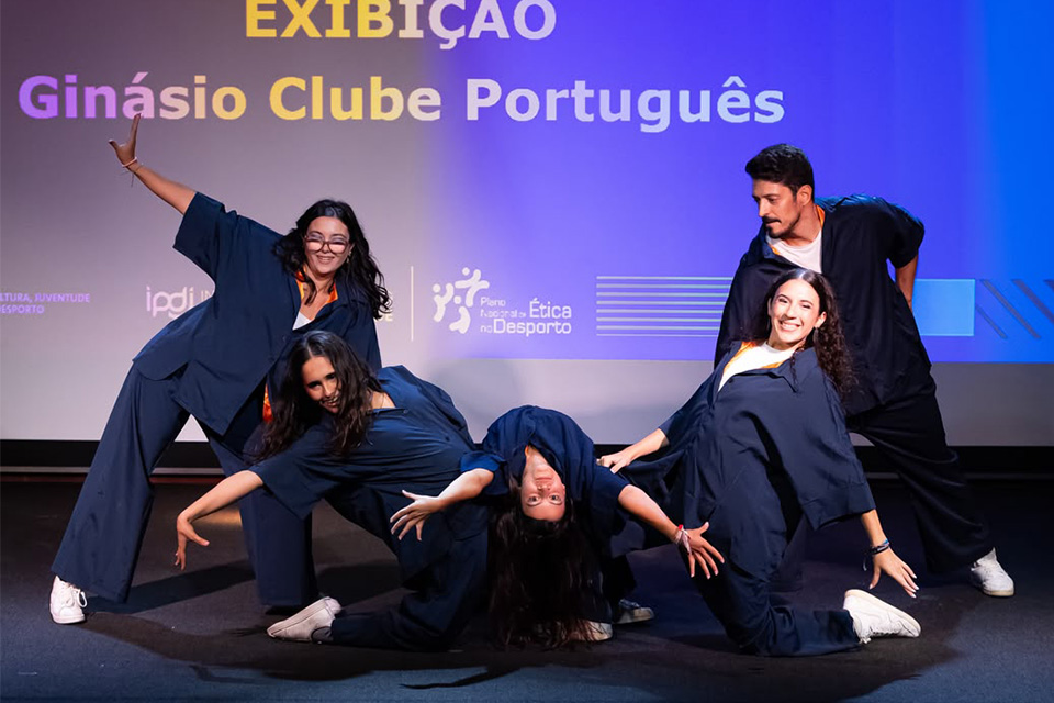 Grupo de atletas do Ginásio Clube Português apresenta coreografia em palco durante exibição.  Forneça o seu feedback sobre o BizChat