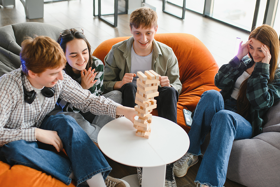 Jovens reunidos em volta de uma mesa a jogar jenga