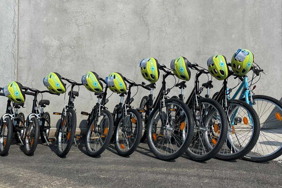 conjunto de bicicletas e capacetes alinhados contra uma parede