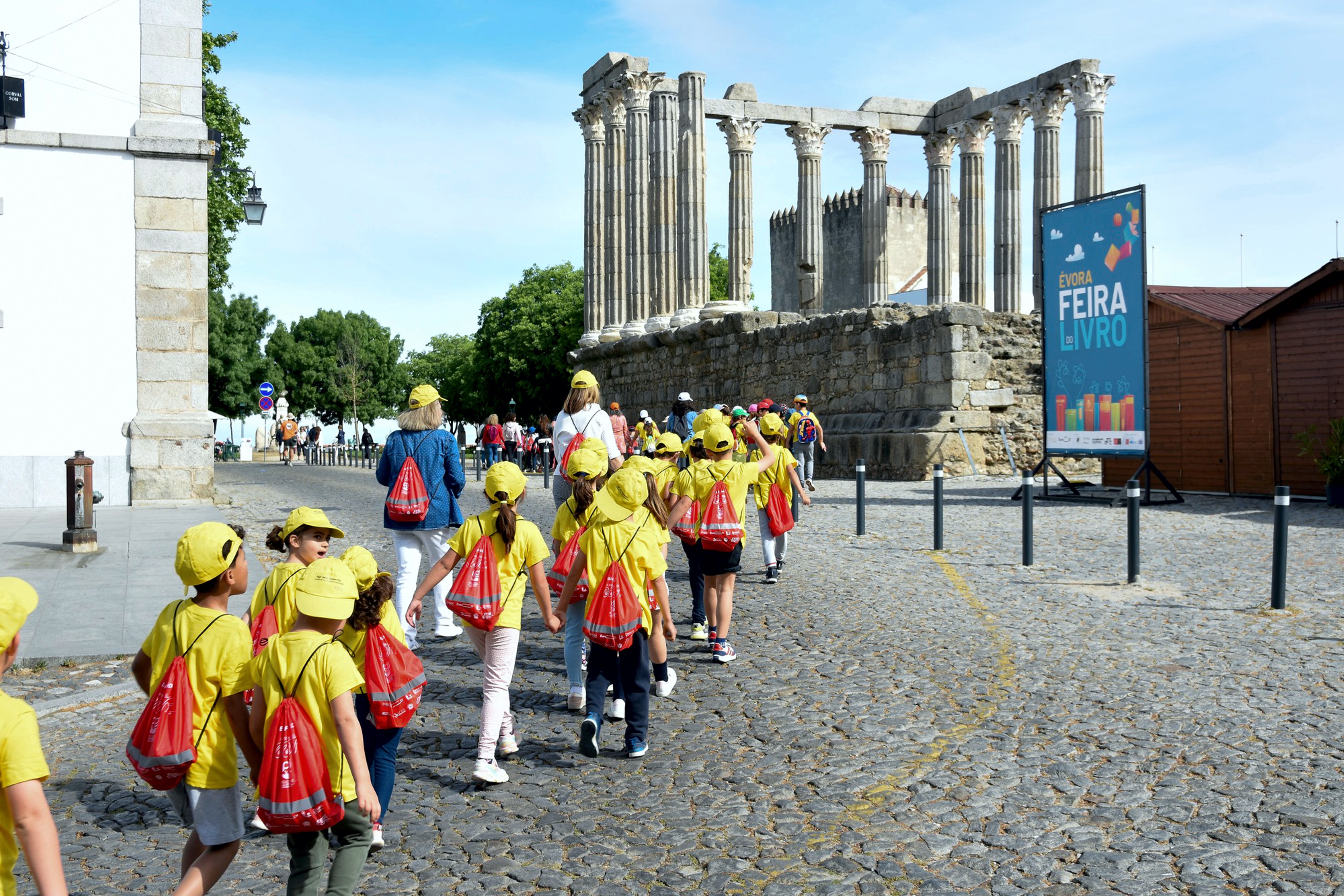 Caminhada das Escolas junto ao Templo Romano, professores e vários alunos com o saco/mochila, vermelho, às costas.