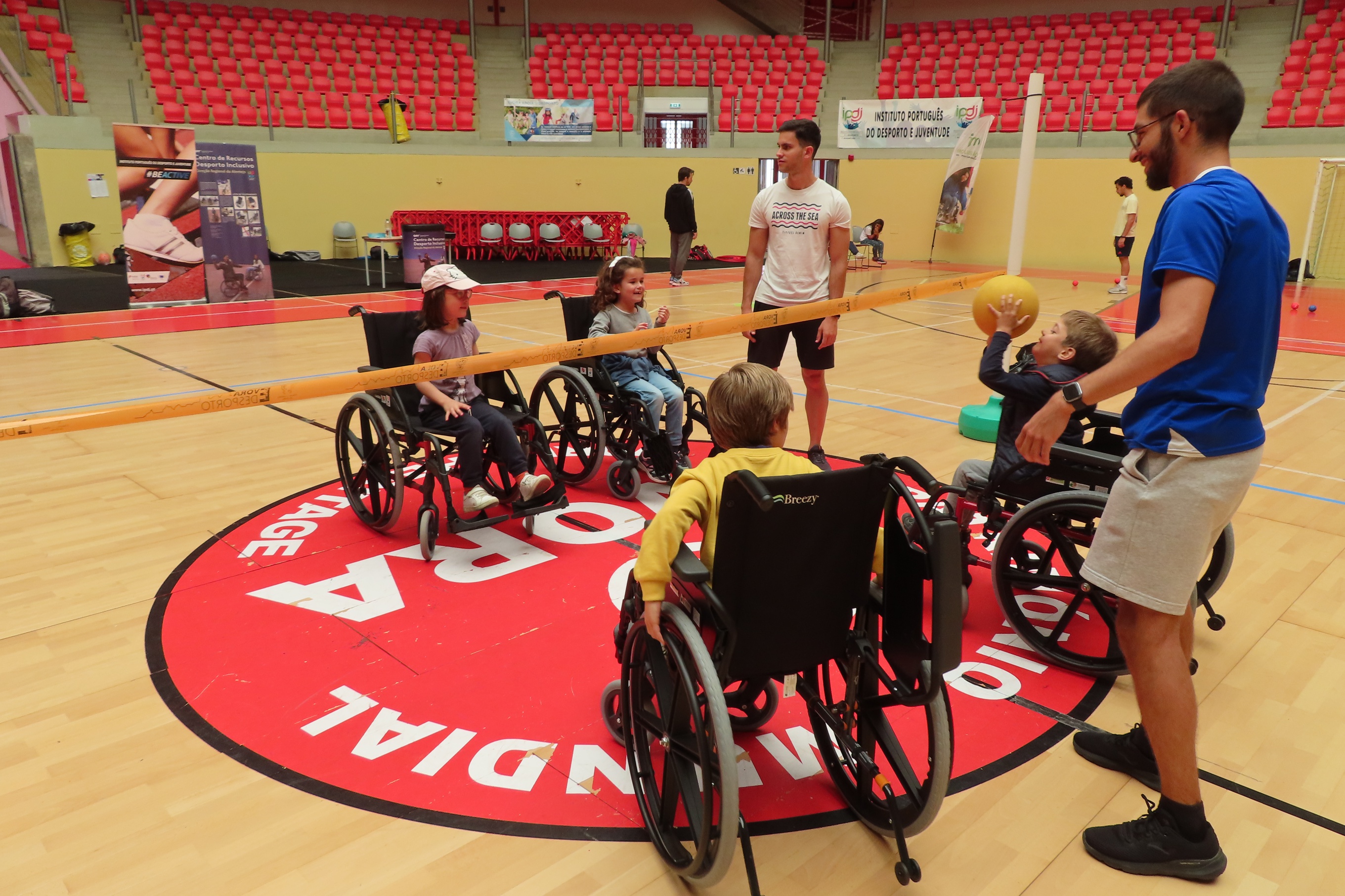 Quatro crianças sem necessidaes especiais, e dois jovens voluntários, na Arena D' Évora, a participarem na atividade de vólei adaptado.