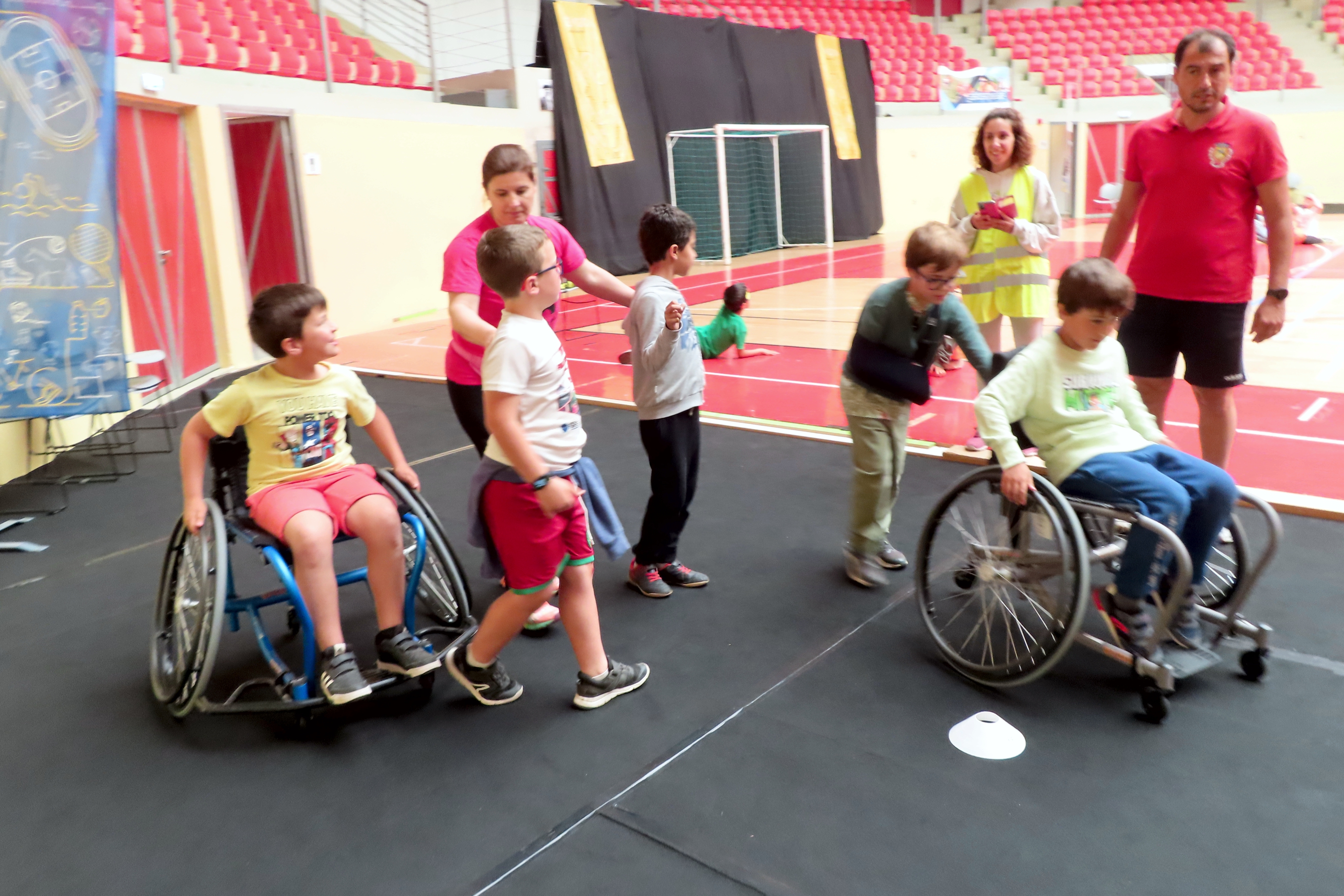 Crianças a experimentarem o equipamento de desporto adaptado, com o apoio de uma técnica do IPDJ e um técnico da Câmara Municipal de Évora, na Arena D' Évora.