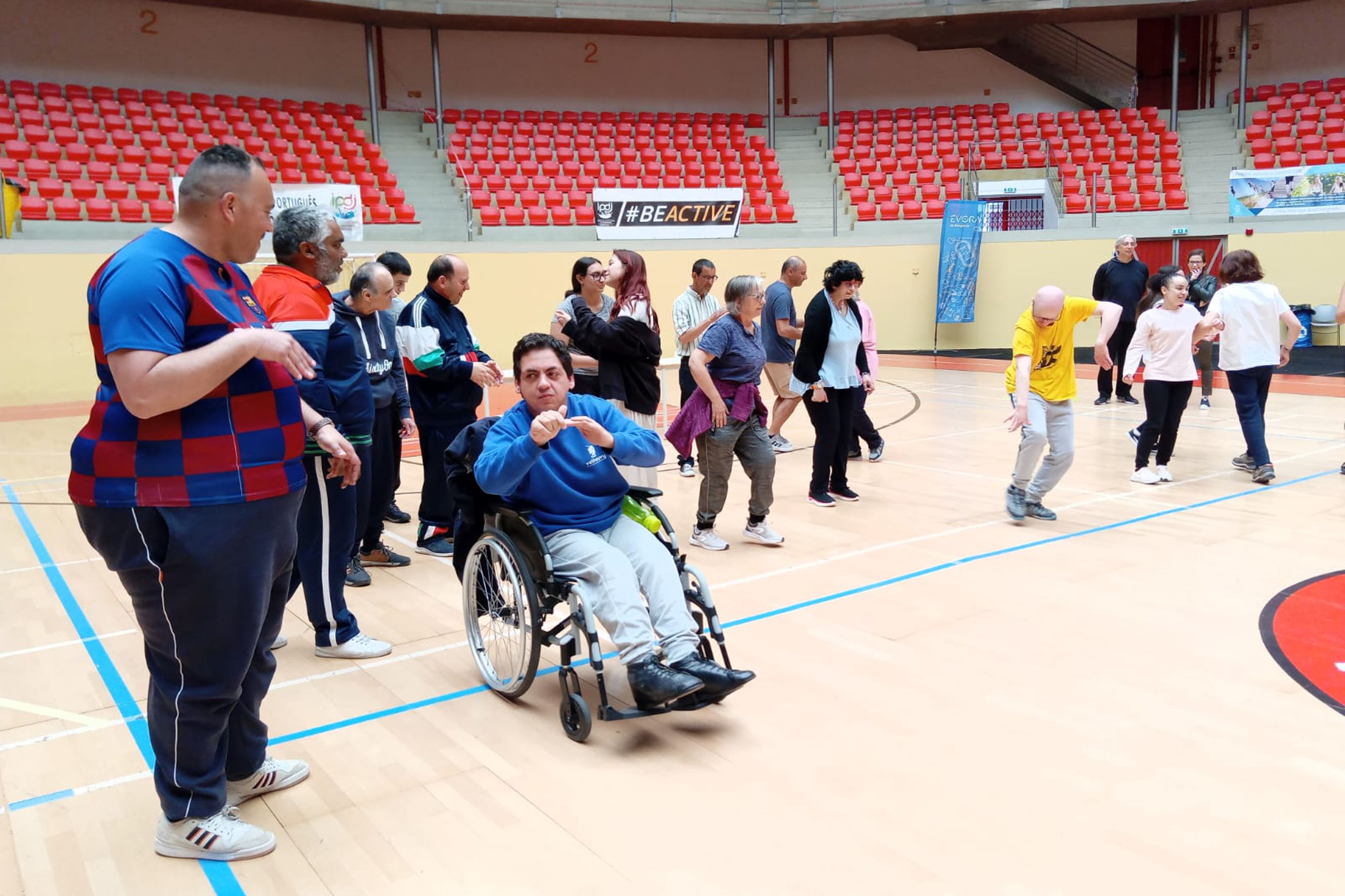 Várias pessoas com necessidades especiais e técnicos, na Arena D' Évora, a participarem na atividade de dança.