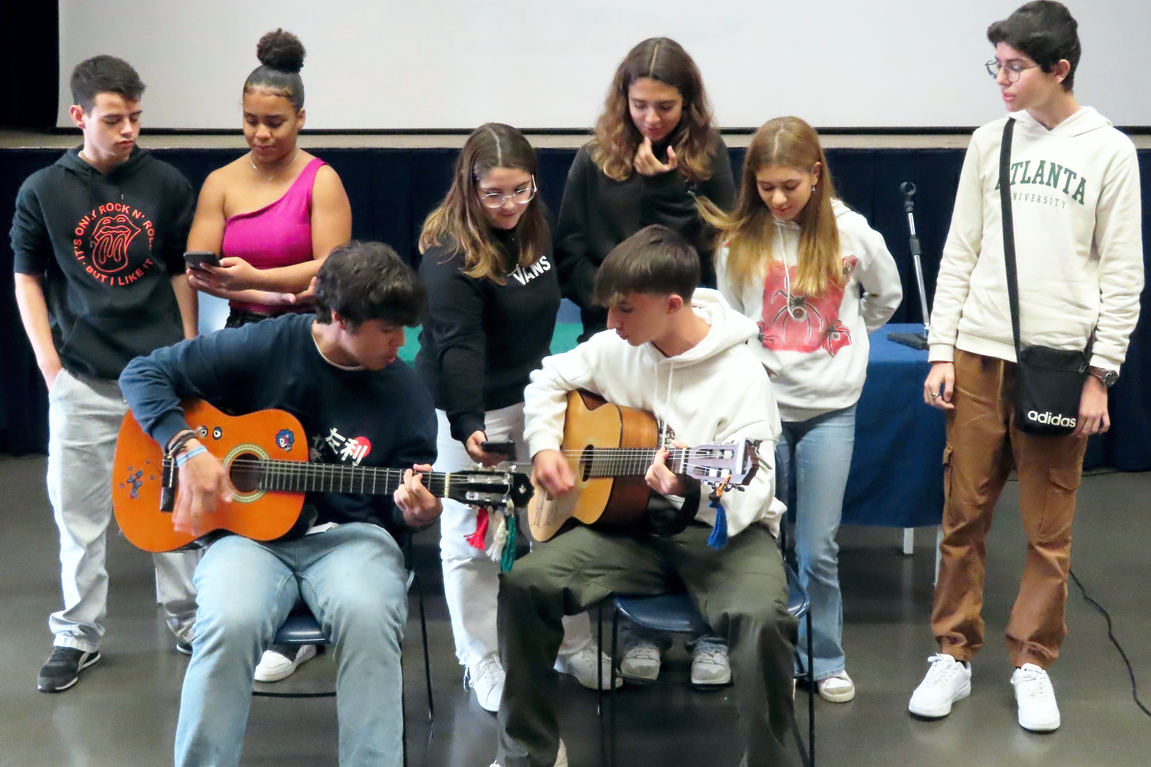 Grupo de jovens a tocar guitarra e a cantar na presentação do seu projeto.