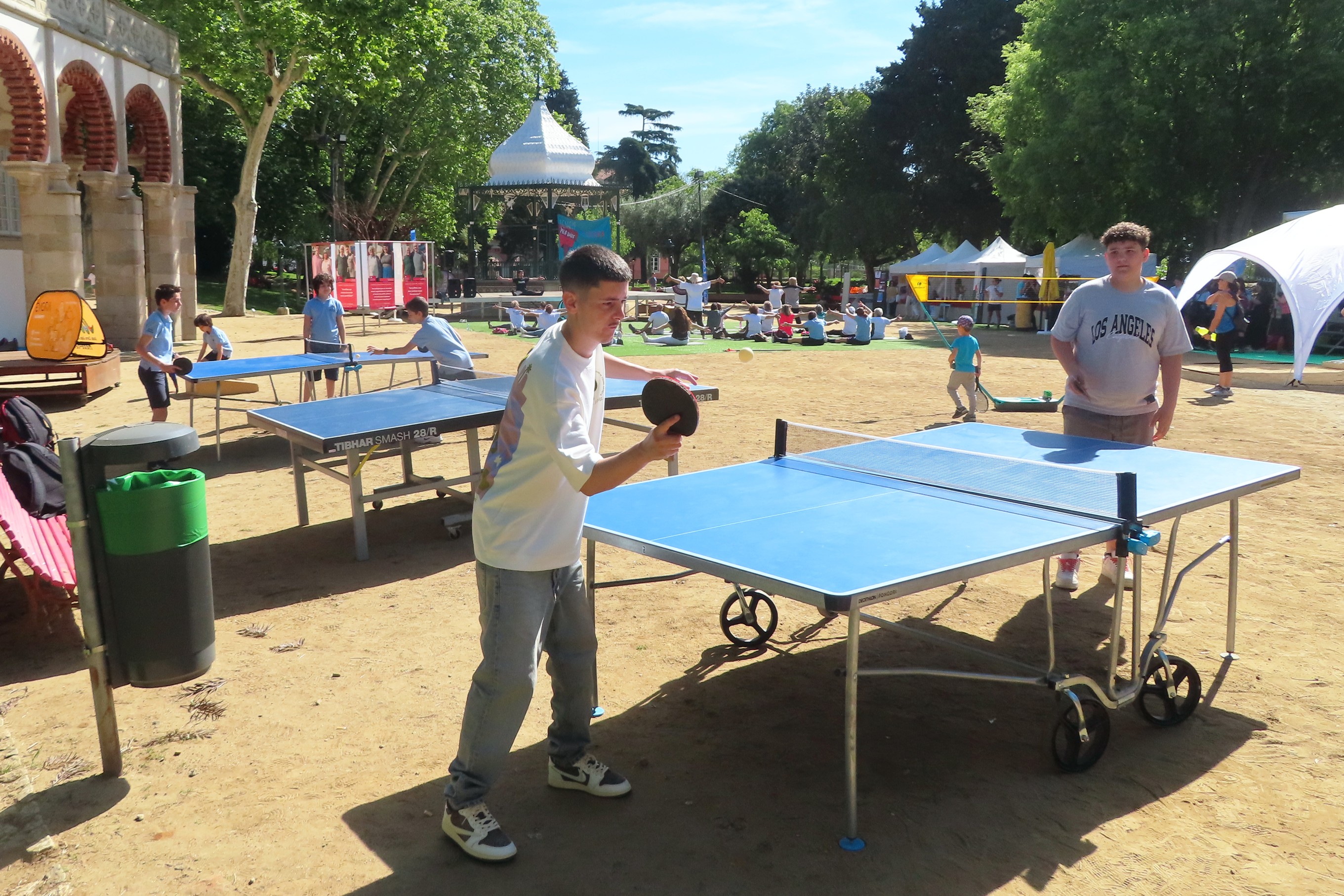 Vários jovens no Jardim Público a jogarem ping pong.
