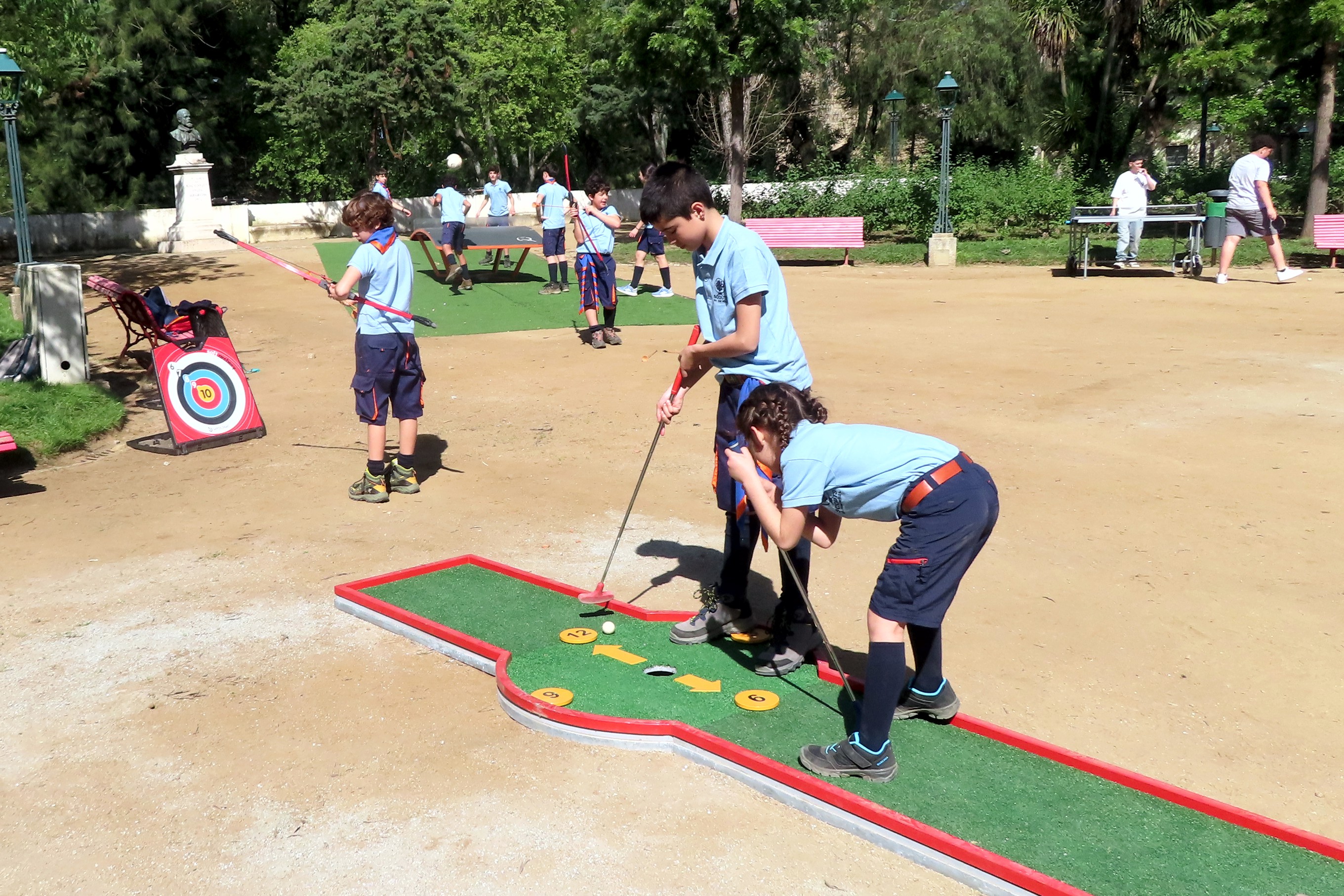 Crianças no JardimPúblico a jogarem mini golfe e tiro ao arco.