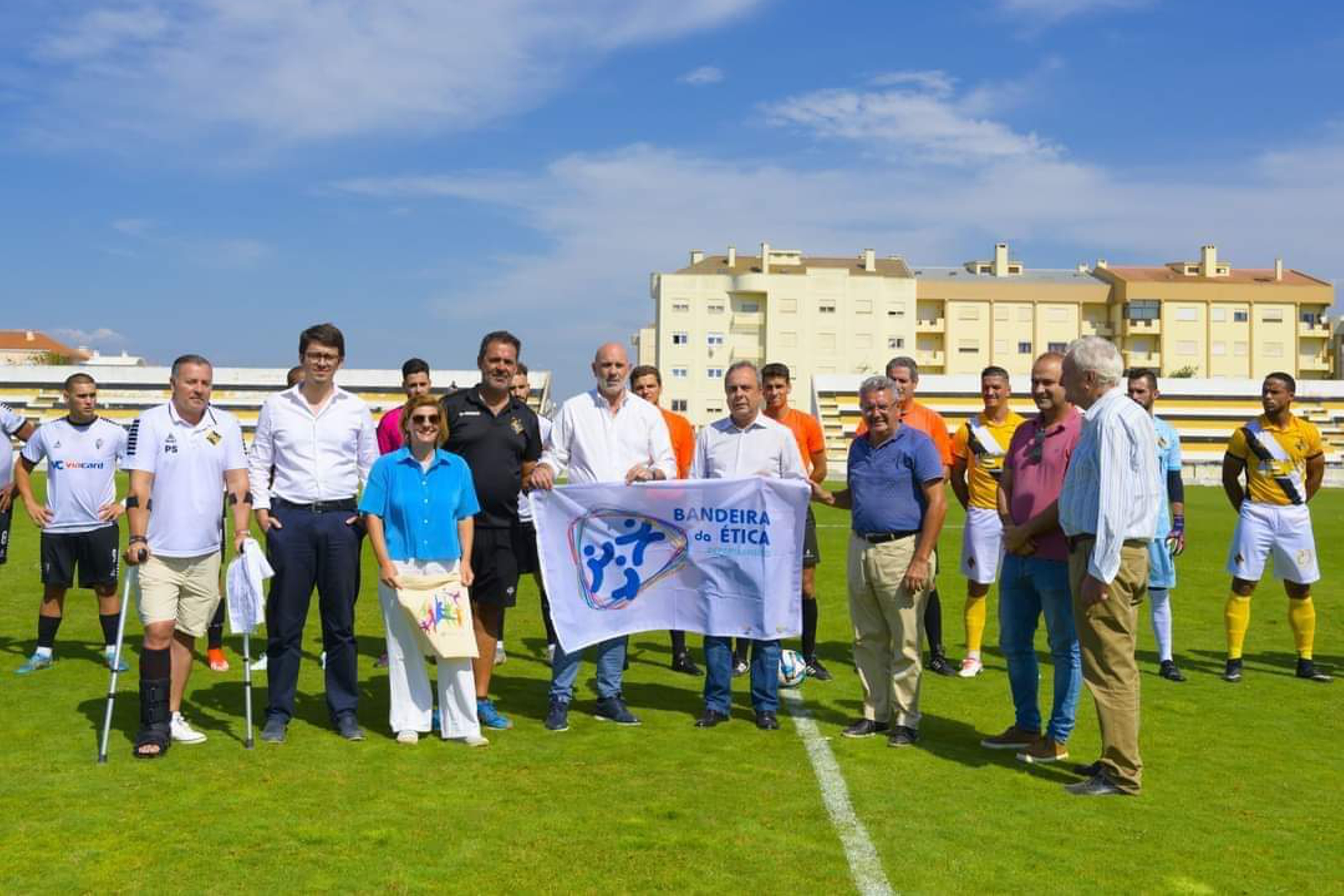 diretor regional do Alentejo do IPDJ, Miguel Rasquinho, presidente do Município de Sines, Nuno Mascarenhas, do vereador do Município de Sines, Gonçalo Naves, do presidente do Vasco da Gama Atlético Clube, Rui Pimenta, do presidente da Associação de Futebol de Setúbal, Amadeu Mota, e da técnica de desporto do IPDJ Alentejo, Andreia Peixe, a segurarem a Bandeira da Ética. Atrás dos representantes de cada uma destas, entidades, estão alguns atletas do Vasco da Gama Atlético Clube.