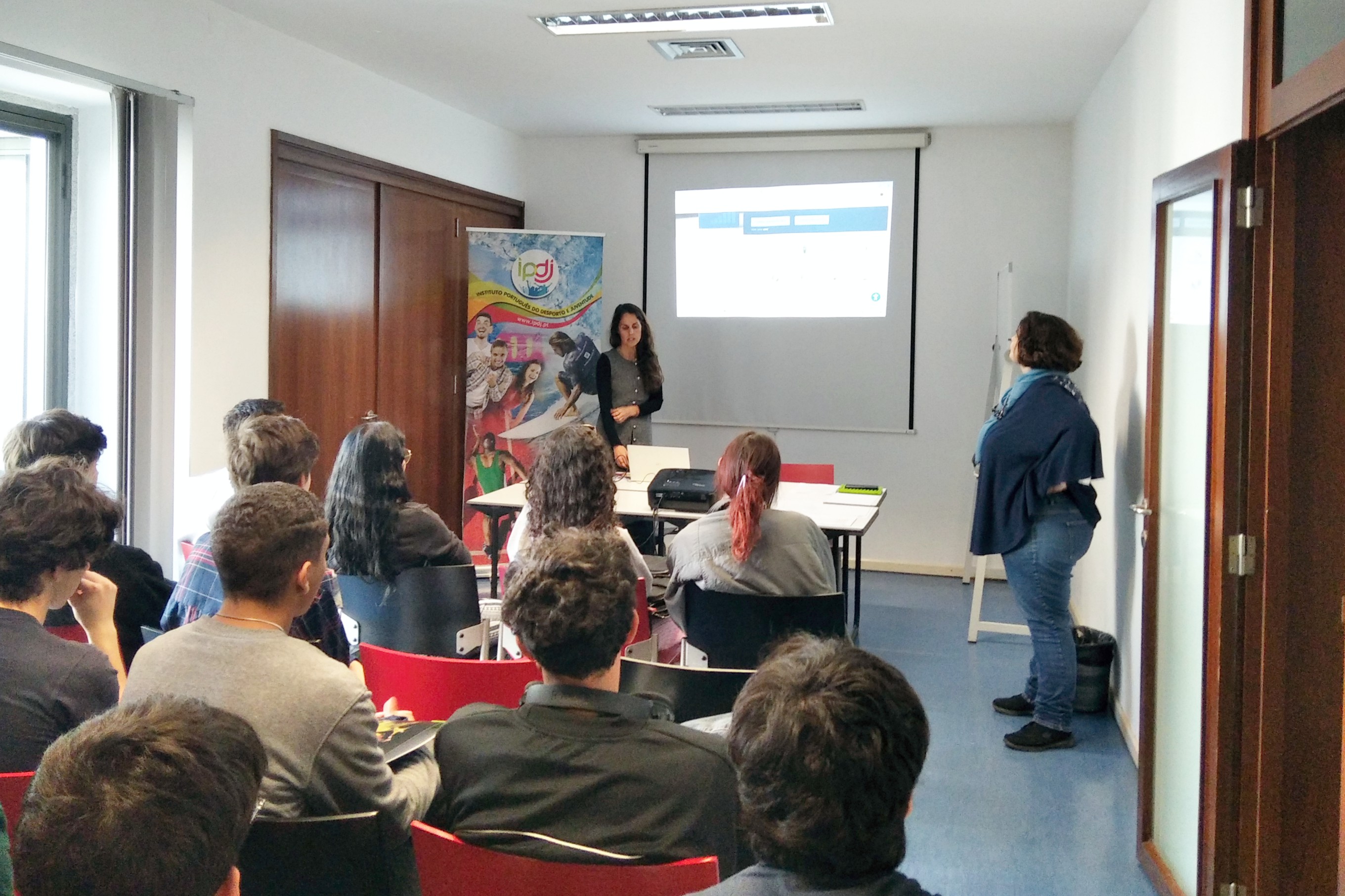 Jovens, professores, representantes de entidades, em sala, na ação de informação e sensibilização sobre os «Jovens e a Prevenção Rodoviária», dinamizada pela técnica da Autoridade Nacional de Segurança Rodoviária e pela técnica do IPDJ de Évora, Gabriela Segurado.