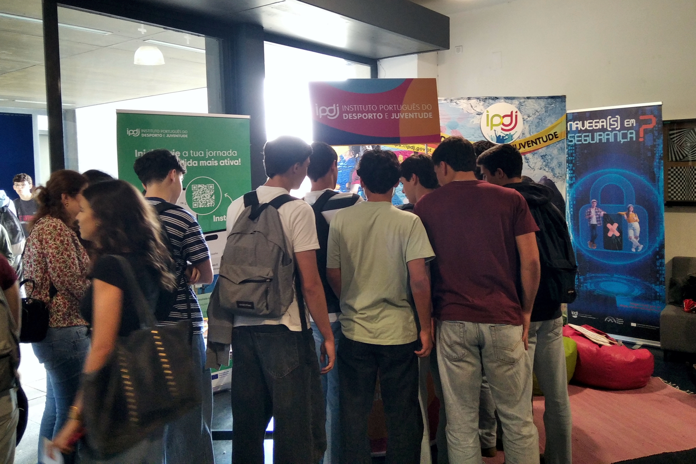 Jovens junto ao stand do IPDJ a participarem nas atividades dinamizadas por uma voluntária IPDJ, aluna da Escola Secundária Severim de Faria.