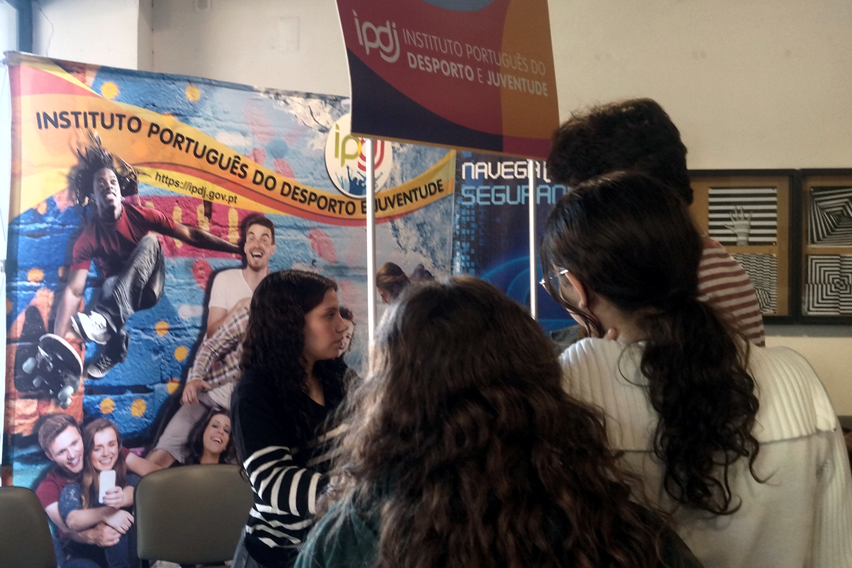 Jovens junto ao stand do IPDJ a participarem nas atividades dinamizadas por uma voluntária IPDJ, aluna da Escola Secundária Severim de Faria.
