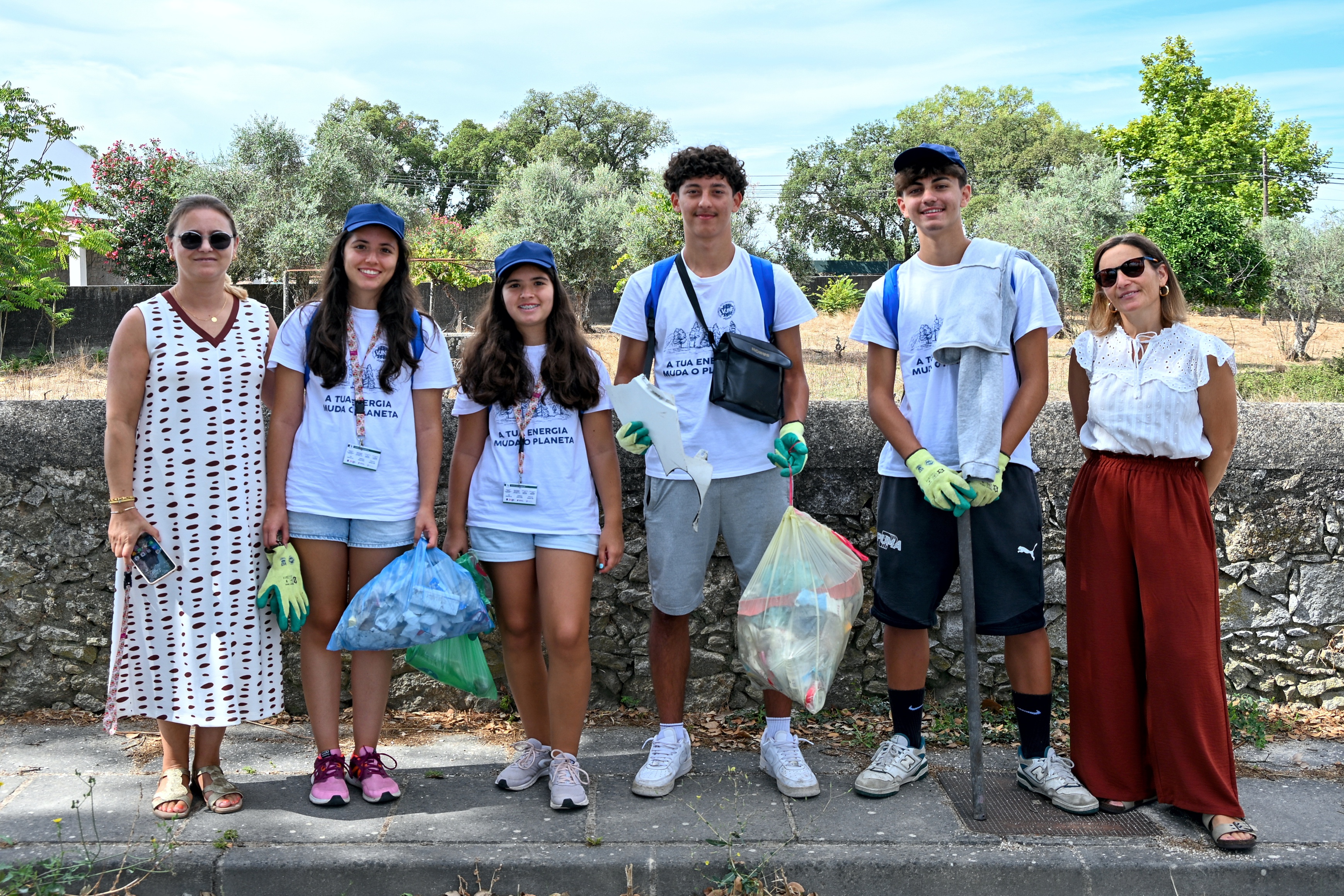 Fotografia de grupo, dos quatro jovens voluntários com o lixo recolhido, durante a atividade, com as responsáveis pelo projeto.