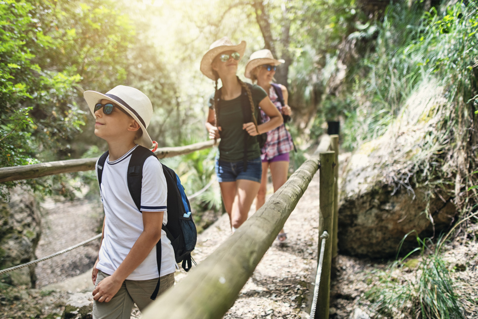 jovens, com ar de veraneio, atravessam ponte suspensa.
